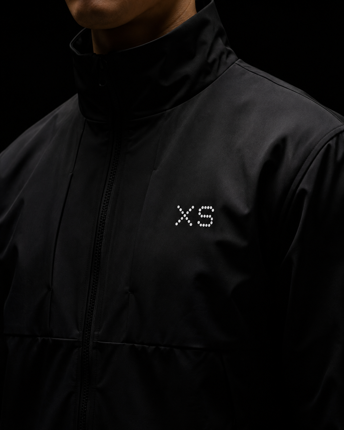 XS dot-matrix mark on a black technical jacket